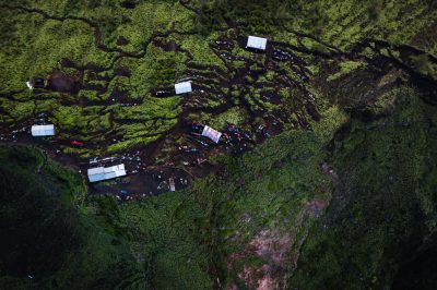 An aerial shot of hills covered in greenery surrounded by buildings under the sunlight